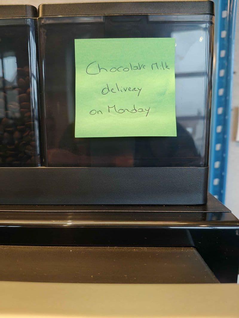 A Post-it on a coffee machine saying: "Chocolate milk delivery on Monday"
